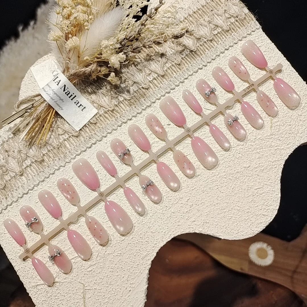 Rosa cat eye-lösnaglar med rosett och glasperlador